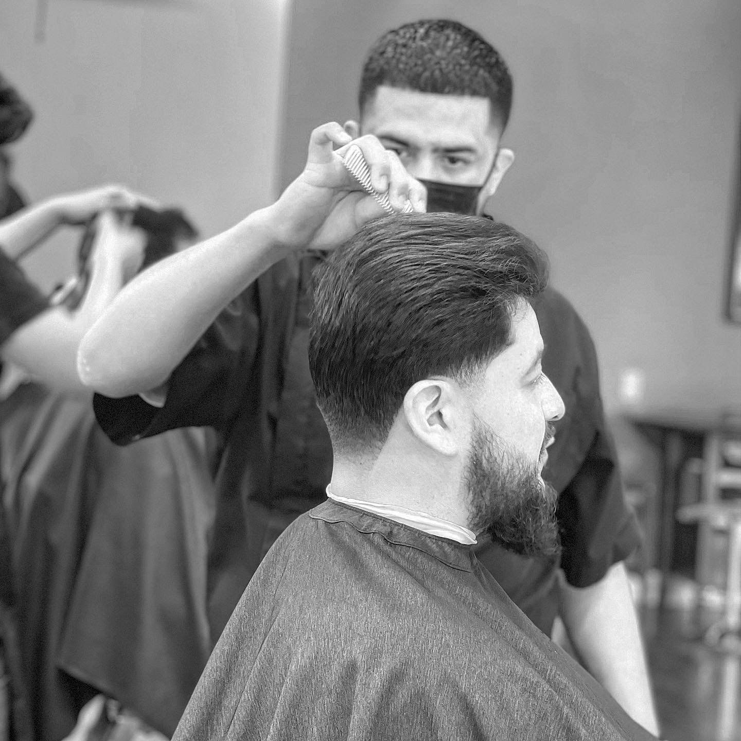 Geo cutting a client's hair with scissor over comb